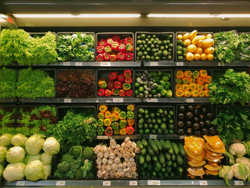 Produce aisle: crates of fresh vegetables including lettuce, peppers, cucumbers, squash, and broccoli
